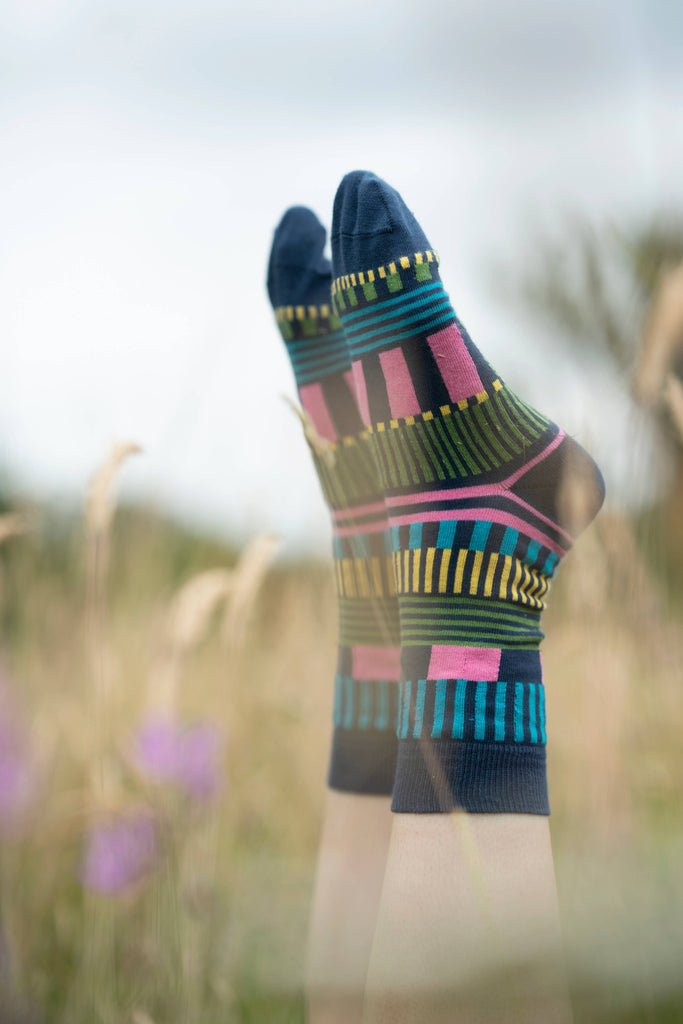 Colorful patterned socks worn in a field with blurred background