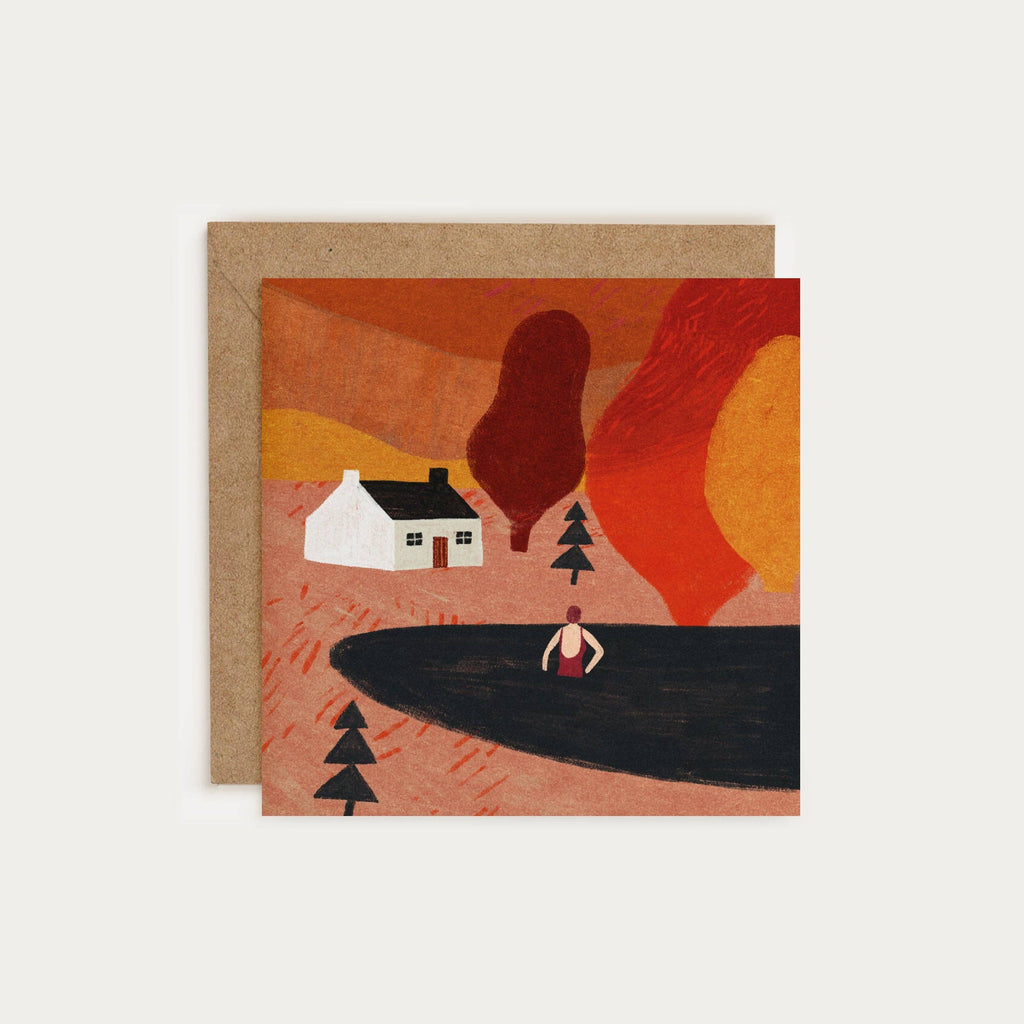 Greeting card with a stylized illustration of a house, trees, and a person by a lake against an orange sky.