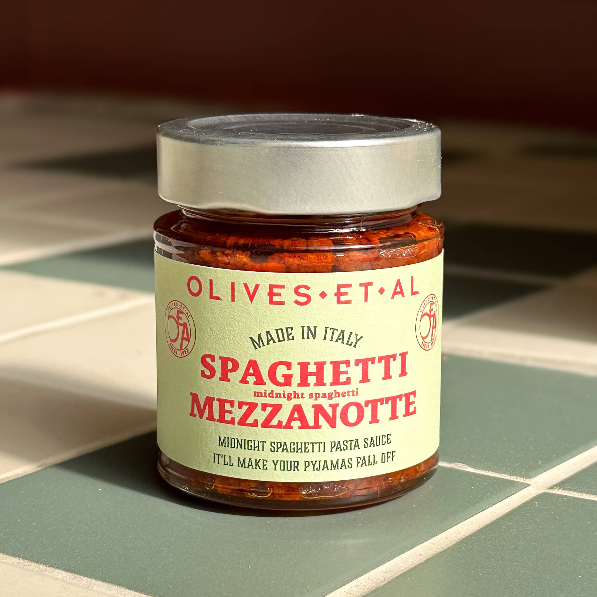 olives et al - jar of spaghetti mezzanotte pasta sauce on tiled surface - winter's moon