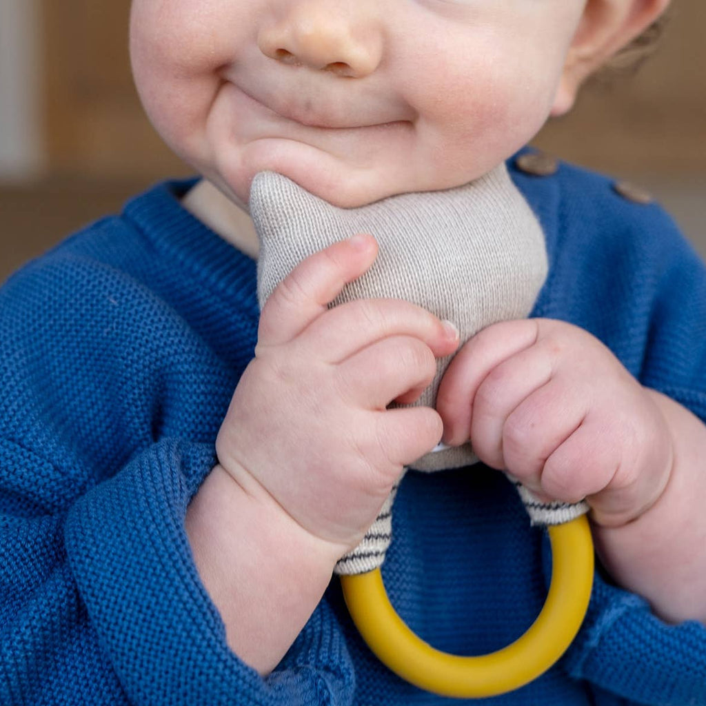 Baby in a blue sweater holding a gray and yellow toy