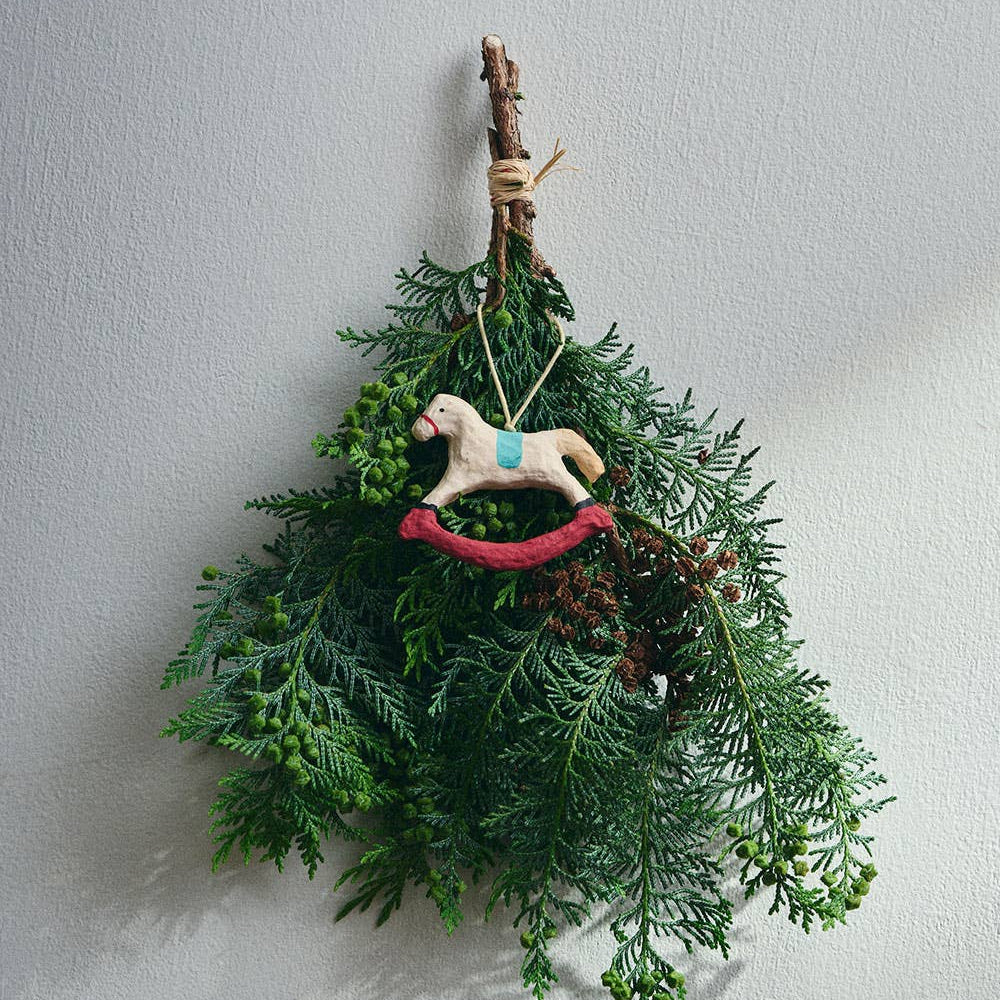 Paper mache rocking horse christmas decoration, attached to a decorative wreath.