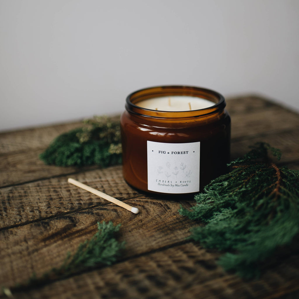 Candle with a label on a wooden surface with greenery