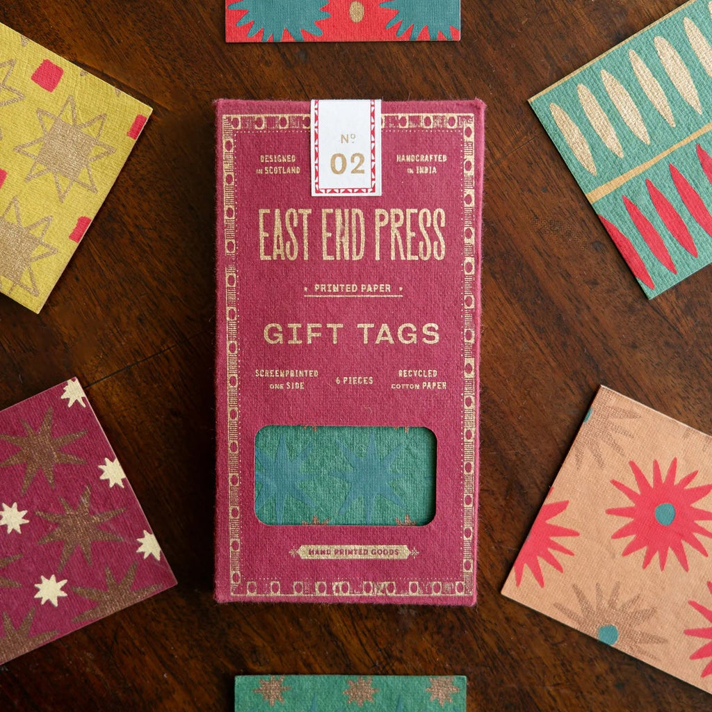 Box of East End Press gift tags with variously patterned gift tags on a wooden surface