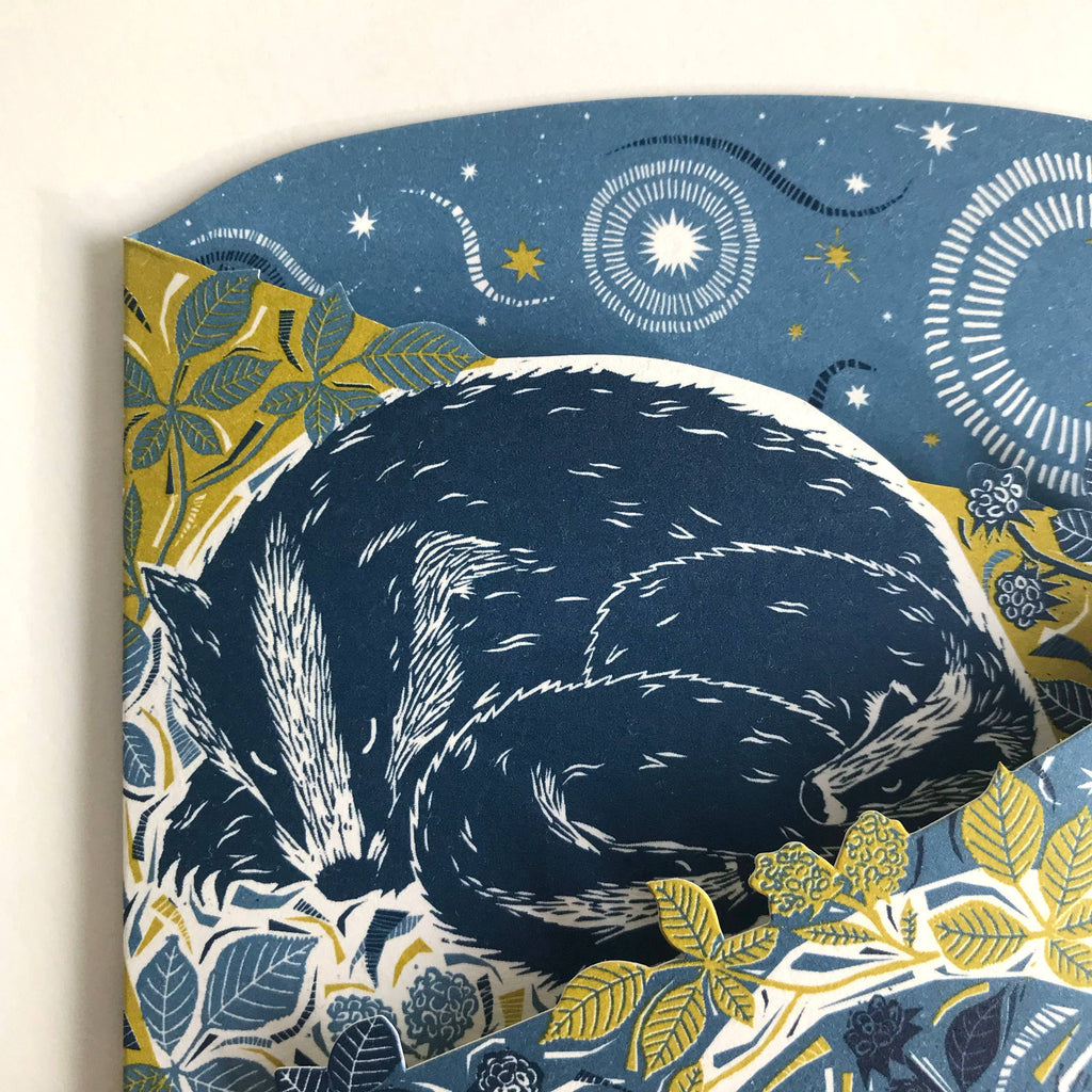Close-up of card featuring a navy blue badger on a floral and starry background