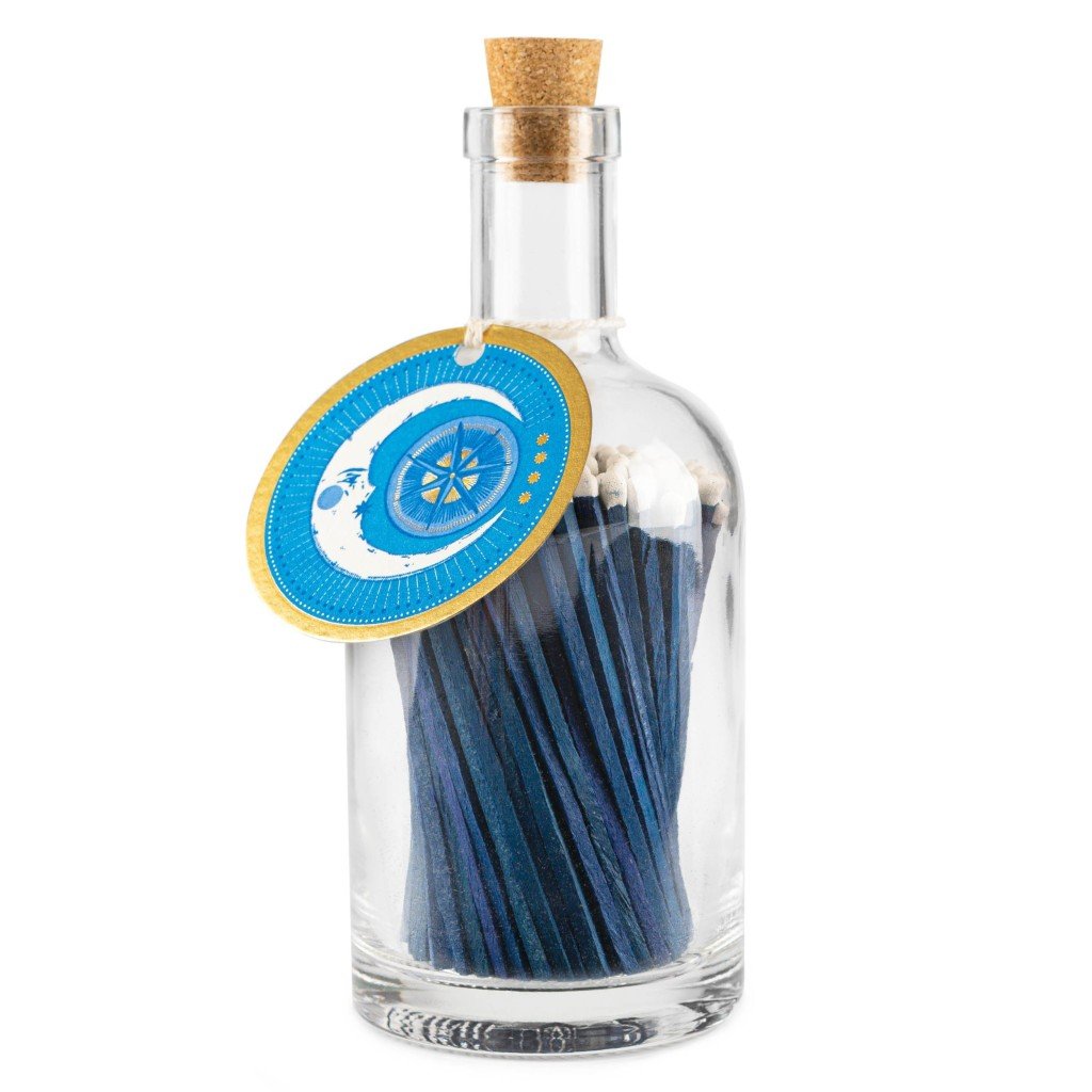 Glass bottle of navy-coloured matches, with a cork stopper and a tag around the neck withg a gold moon illustration.  
