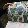 Hand holding a page with floral and plant illustrations, featuring the month of February.