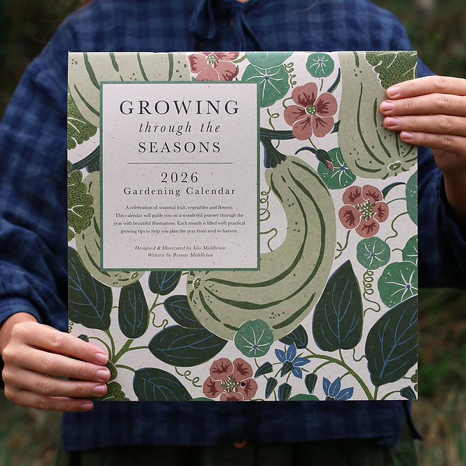 Gardening calendar titled 'Growing through the Seasons 2026' held by a person.