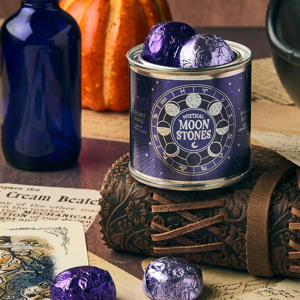 Canister labeled 'Mystical Moon Stones' with wrapped chocolates on a wooden surface with vintage items.