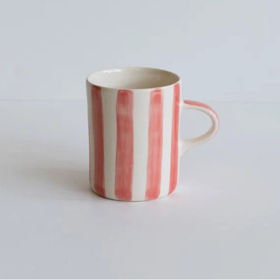 Ceramic mug with pink and white striped pattern on a light grey background