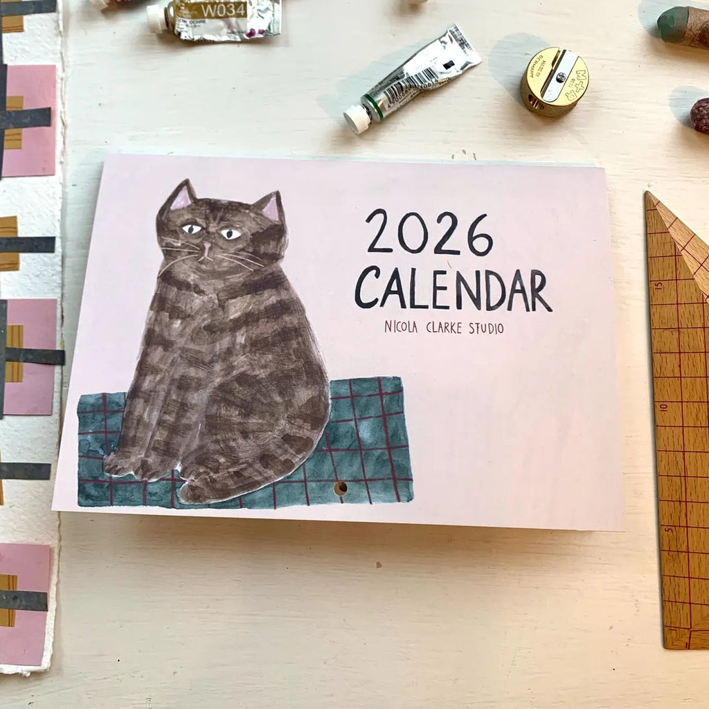2026 calendar with a cat illustration on a table with stationery items