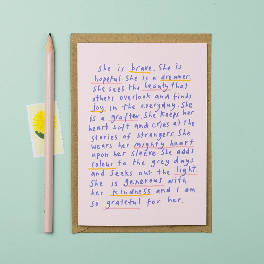 Handwritten poem on a pink card with a pencil and yellow flower on a light blue background