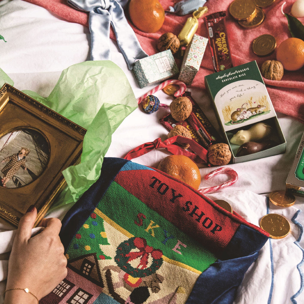 Person holding a vintage photo album with a Christmas-themed toy shop scene and various Christmas items.