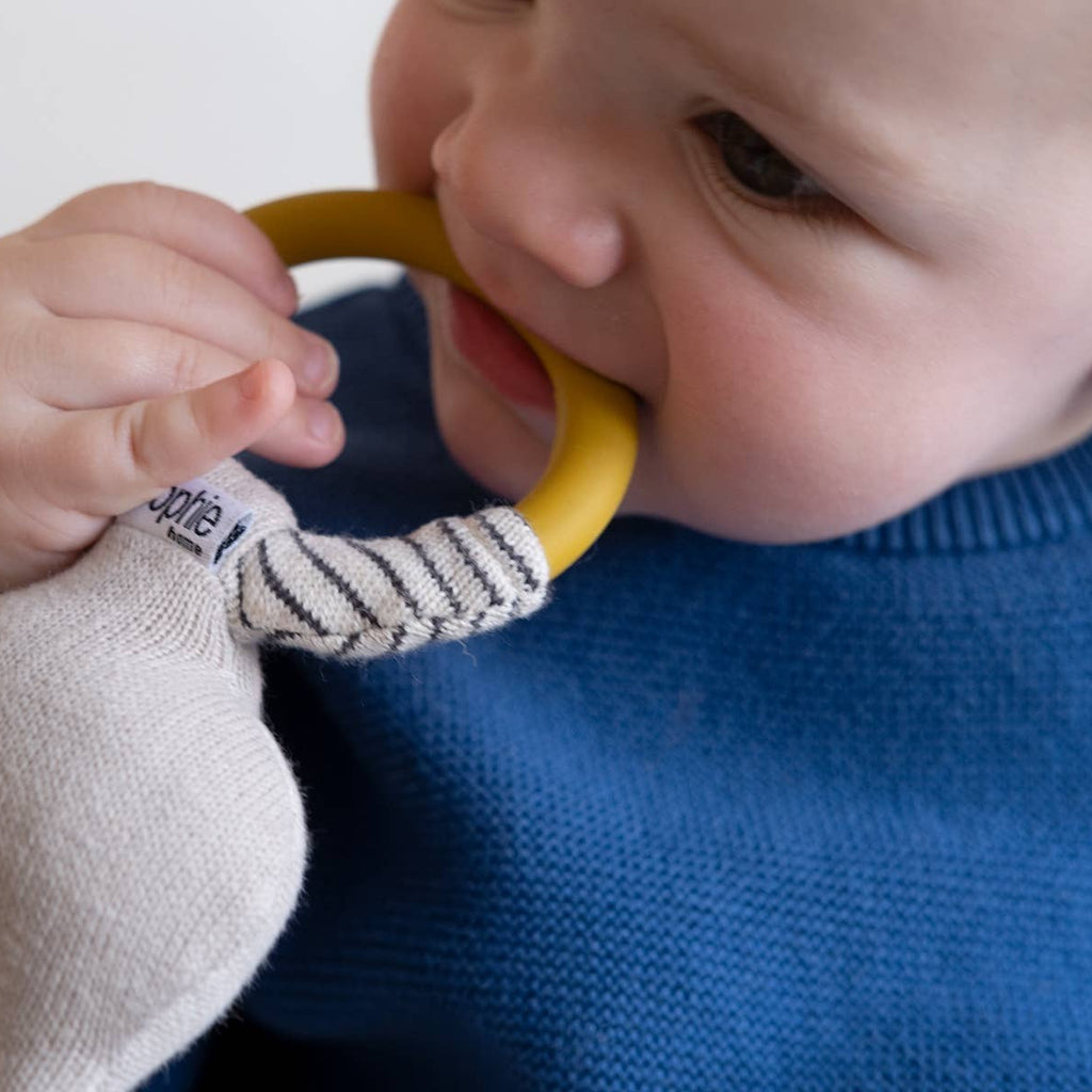 Baby holding a teething ring with a visible brand logo