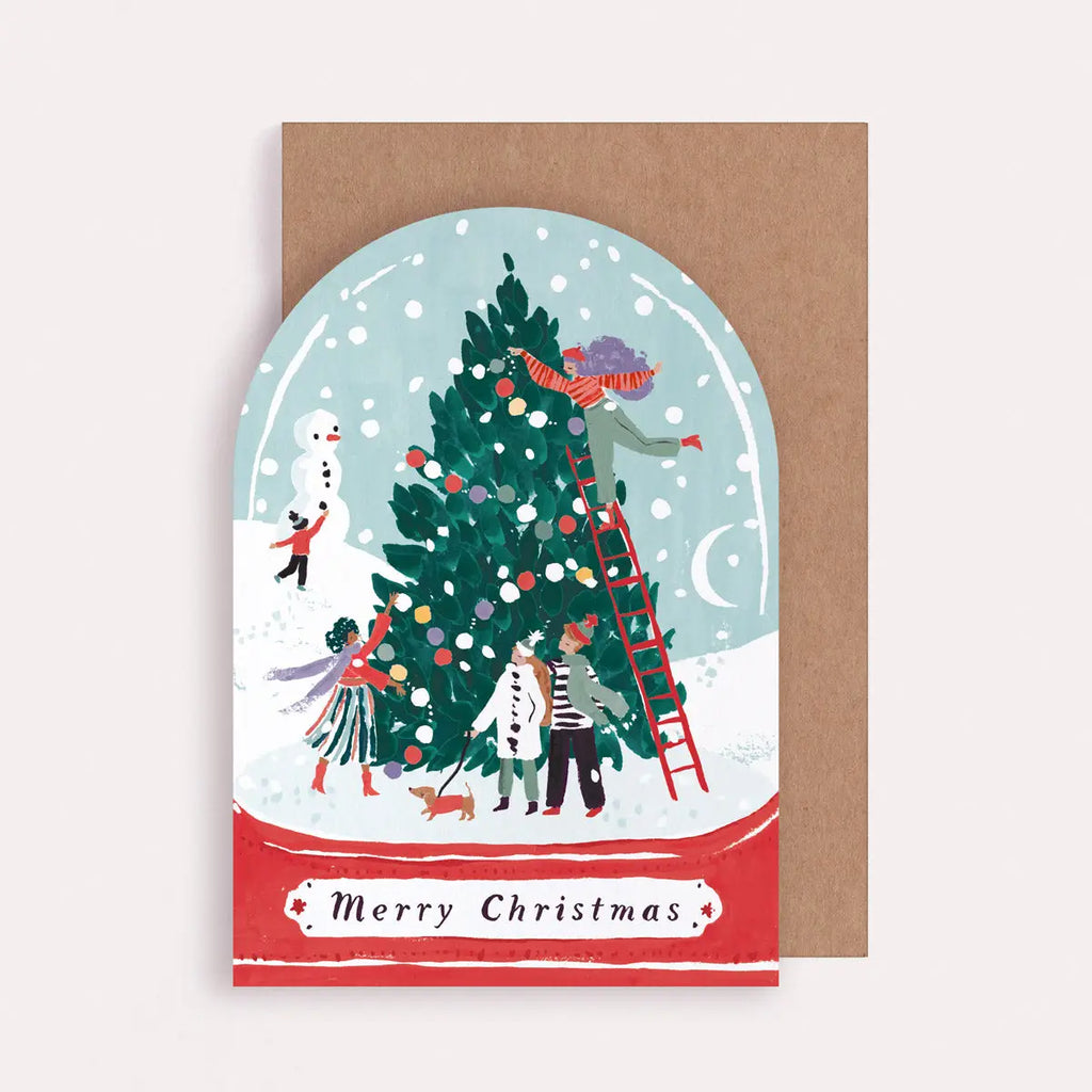 Christmas card with illustration of people decorating a tree, inside a snow globe, on a brown envelope.