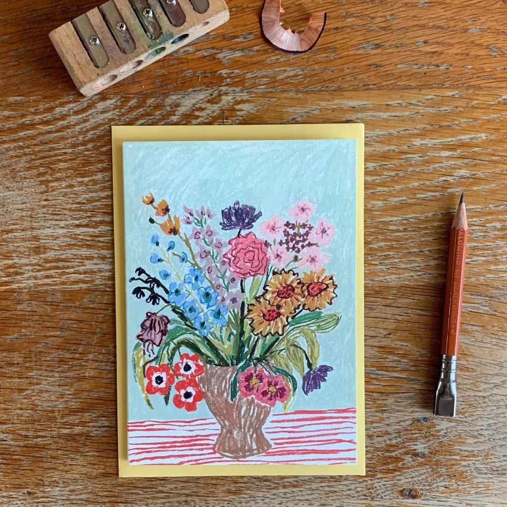 An A6 illustrated card, with a pencil illustration of a bouquet of flowers in a vase on a striped tablecloth by artist Nicola Clarke.