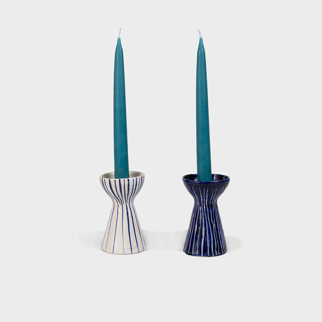 Navy and white striped candleholders, pictured with an aquamarine tapered candle. 