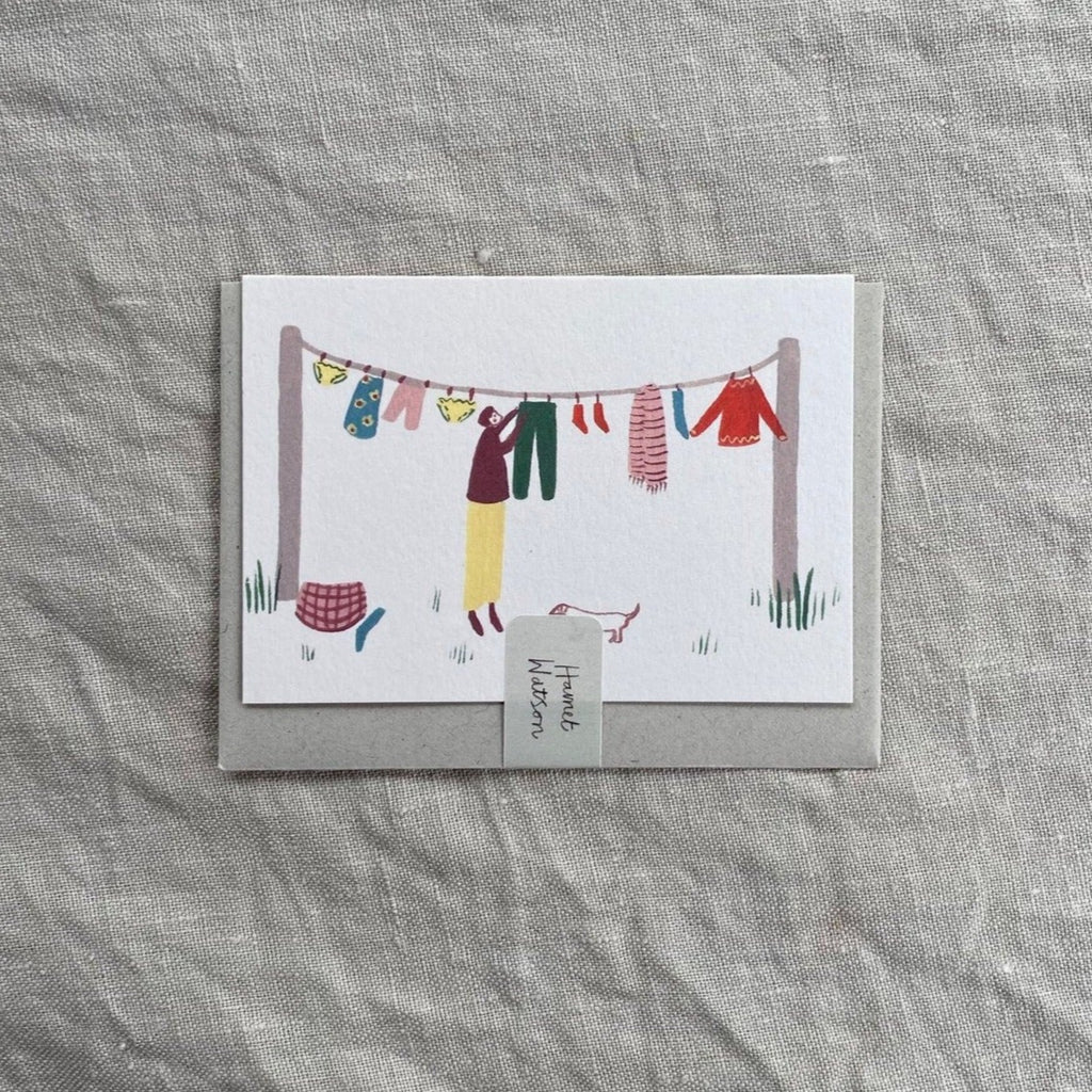 A7 sized mini card, with a painted gouache illustration by artist harriet watson, of a figure hanging out washing.